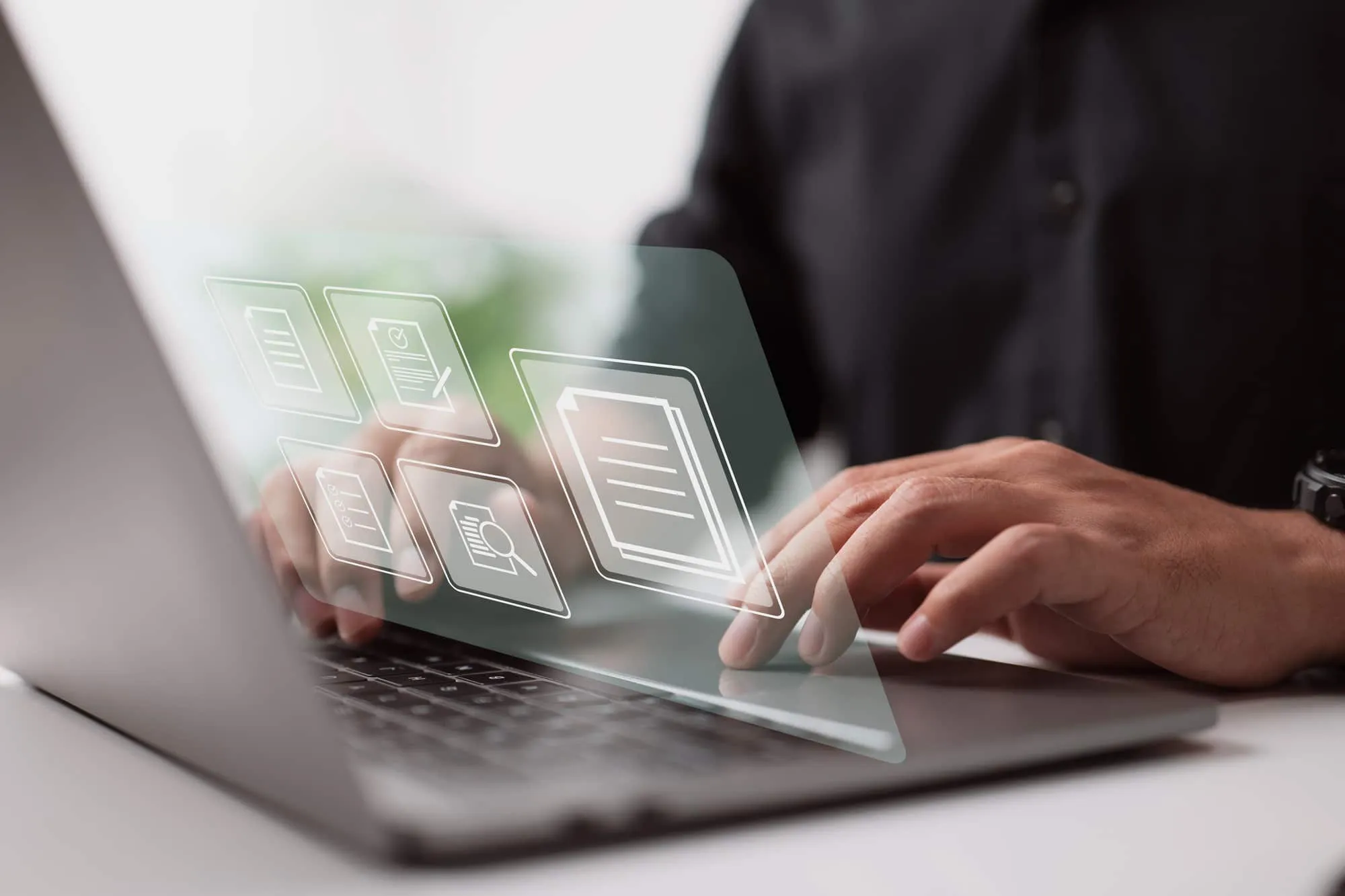 Main sur le clavier d'un ordinateur portable, icônes de documents en surimpression translucide